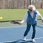 An older woman playing pickleball.