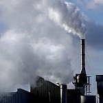 white cloudy emissions emerge from a factory complex