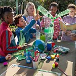  diverse group of six children making environmental art outdoors with an adult