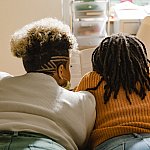 Two woman sitting a bed.