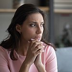 Worried young indian Arabic woman sit on couch at home look in distance thinking pondering, anxious unhappy arab mixed race female suffer from mental psychological personal problems, mourn or yearn