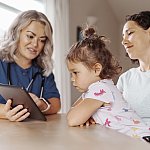 Image of a toddler and two women using a tablet