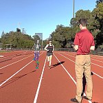 Image shows a researcher using two stationary smartphones to record a study participant jogging