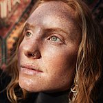A close-up of a young woman's face looking thoughtfully into the sun's direction.
