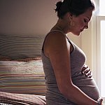 Image of a pregnant woman sitting on a bed