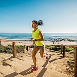 Image of a woman running up stairs near a beach