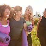 Image of women laughing and holding yoga mats