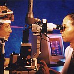 Photo of a female doctor performing laser eye therapy on a female patient