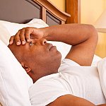 a photo of a man lying awake in bed