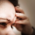 Photo of a woman holding her hand to her head