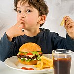 Photo of little boy eating fast food