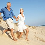 An older couple running down a sand dune.