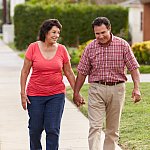 Senior Hispanic couple walking and holding hands on a sidewalk