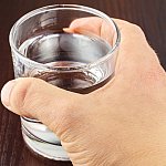 Hand gripping glass of water.