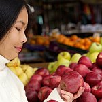 Young woman at store looking at apples