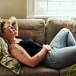 Woman lying on sofa holding her stomach
