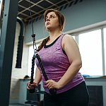 Overweight woman doing weight exercise in gym