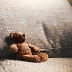 Teddy bear sitting alone on couch