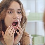 Woman checking the inside of her mouth in a mirror