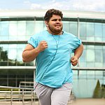 Young man with excess weight running outdoors