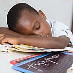 Boy asleep at a desk with his head on a book