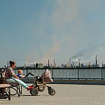 Woman with baby sitting on a bench in a polluted city