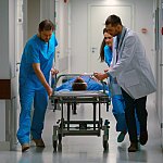 Emergency workers pushing a patient down a hospital corridor.