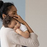 Mother holding infant against chest.