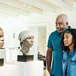 People looking at forensic facial reconstructions of two enslaved African American workers.