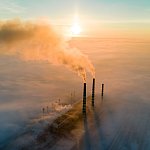 Aerial view of coal power plant with dark smoke at sunset.