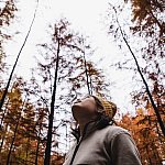 Woman looking up into the sky above the tree tops of a cypress forest