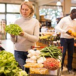 Middle-aged woman shopping for fresh vegetables.