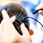 Researcher plugging a cable into a device on a person’s head.