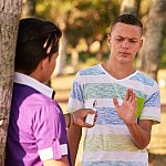 Teenager in a park turning down an electronic cigarette.