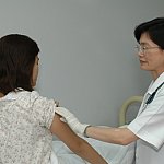 A female doctor giving an injection to a female patient.