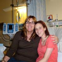 Weller and her daughter, sitting on a hospital bed, smile for the camera