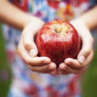 A girl holding a bright red apple