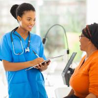 Nurse and senior patient, both African American
