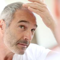 Older man looking at his hair in a mirror