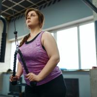 Overweight woman doing weight exercise in gym