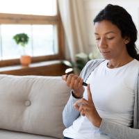 Young woman sitting on a couch doing a glucose test