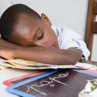 Boy asleep at a desk with his head on a book