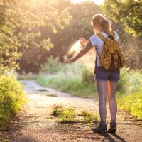 Woman applying insect repellent as mosquitoes fly around her