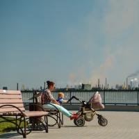 Woman with baby sitting on a bench in a polluted city