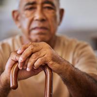 Portrait of a senior man with his hands on a cane.