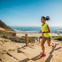 Image of a woman running up stairs near a beach