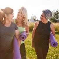 Image of women laughing and holding yoga mats