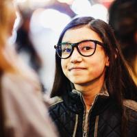 Image of a smiling teenage girl outside with friends on a cold evening.