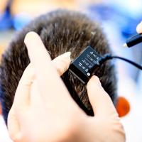 Researcher plugging a cable into a device on a person’s head.