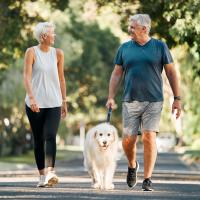an older woman and man walking a dog